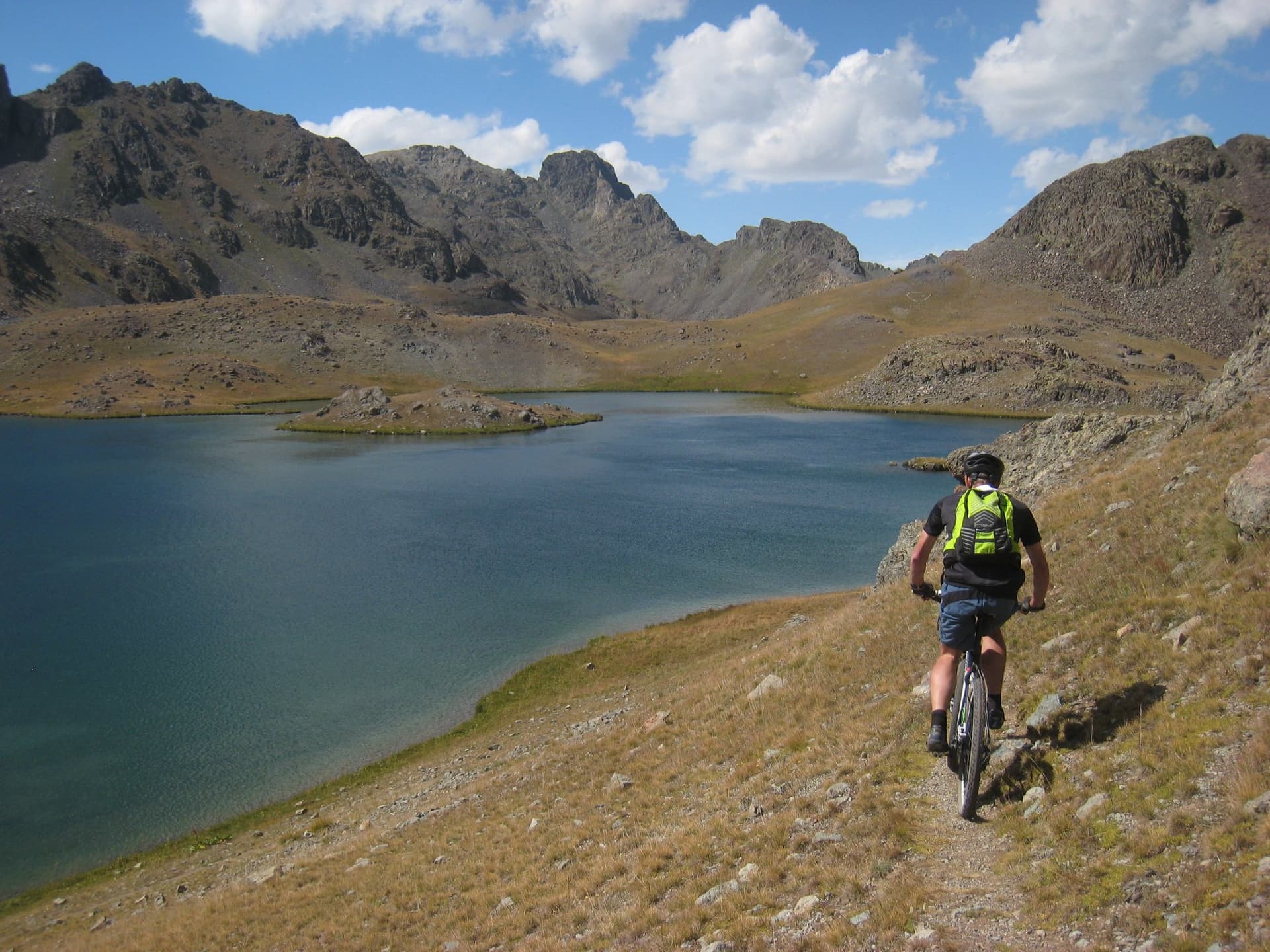 Mountain biker riding the shore of a glacial lake below the jagged peaks of the Kackar Mountains